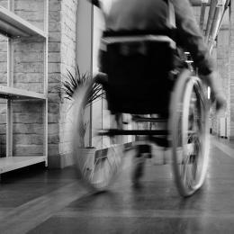 Eine Person in einem Rollstuhl, von hinten in Bewegung fotografiert