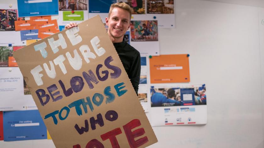Jonas Spiegel hält ein Poster mit der Aufschrift "The Future Belongs to Those Who Vote"
