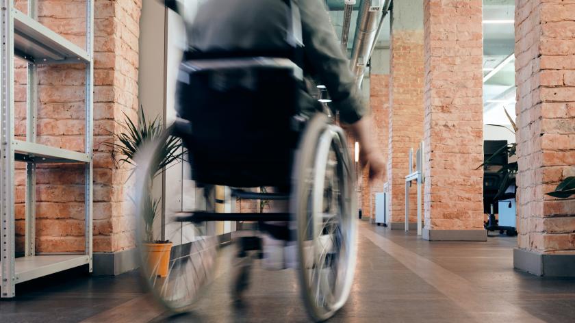 Eine Person in einem Rollstuhl, von hinten in Bewegung fotografiert
