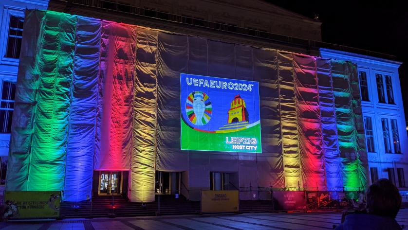 Vor der Oper in Leipzig wird das neue Logo von der Spielstätte Leipzig bei der EM 2024 an die Wand geworfen